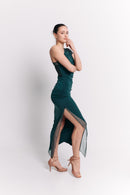 Woman wearing a green dress with a slit on a white background