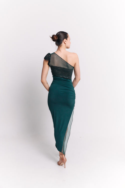 Woman wearing a one-shoulder green dress with sheer panels on a white background