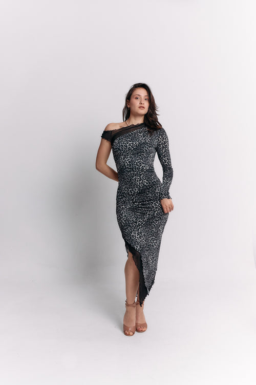 Woman wearing a black and white leopard patterned off-shoulder dress on a light gray background