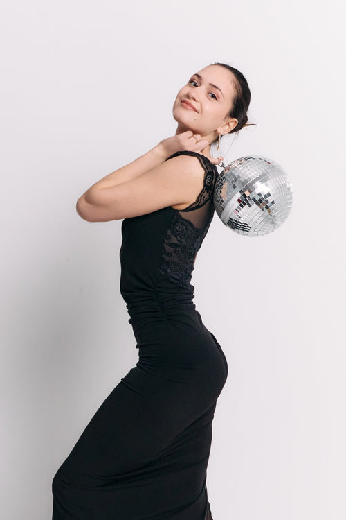 Woman in a black dress holding a disco ball against a white background