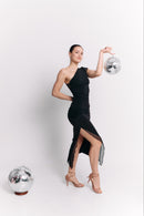 Woman in a black one-shoulder dress holding a disco ball on a white background