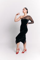 Woman wearing a black dress with sheer sleeve against a white background