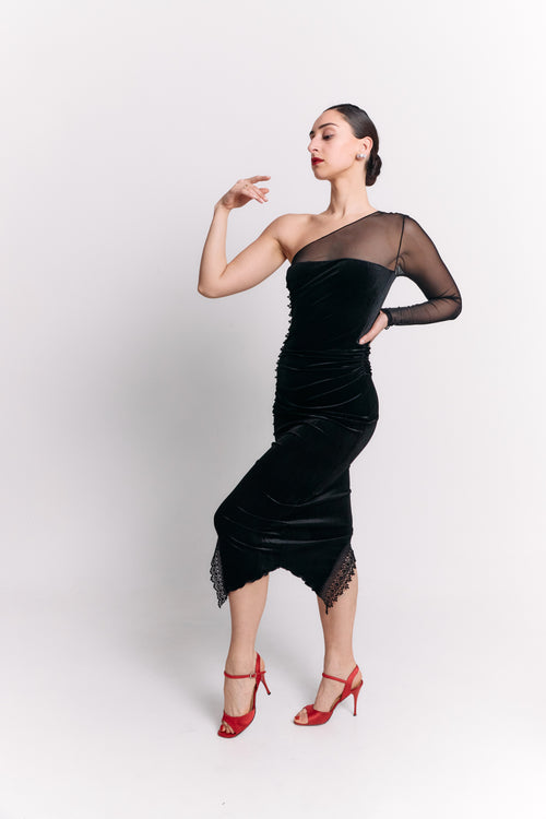 Woman wearing a black dress with sheer sleeve against a white background