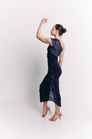 Woman wearing a navy blue lace dress against a white background