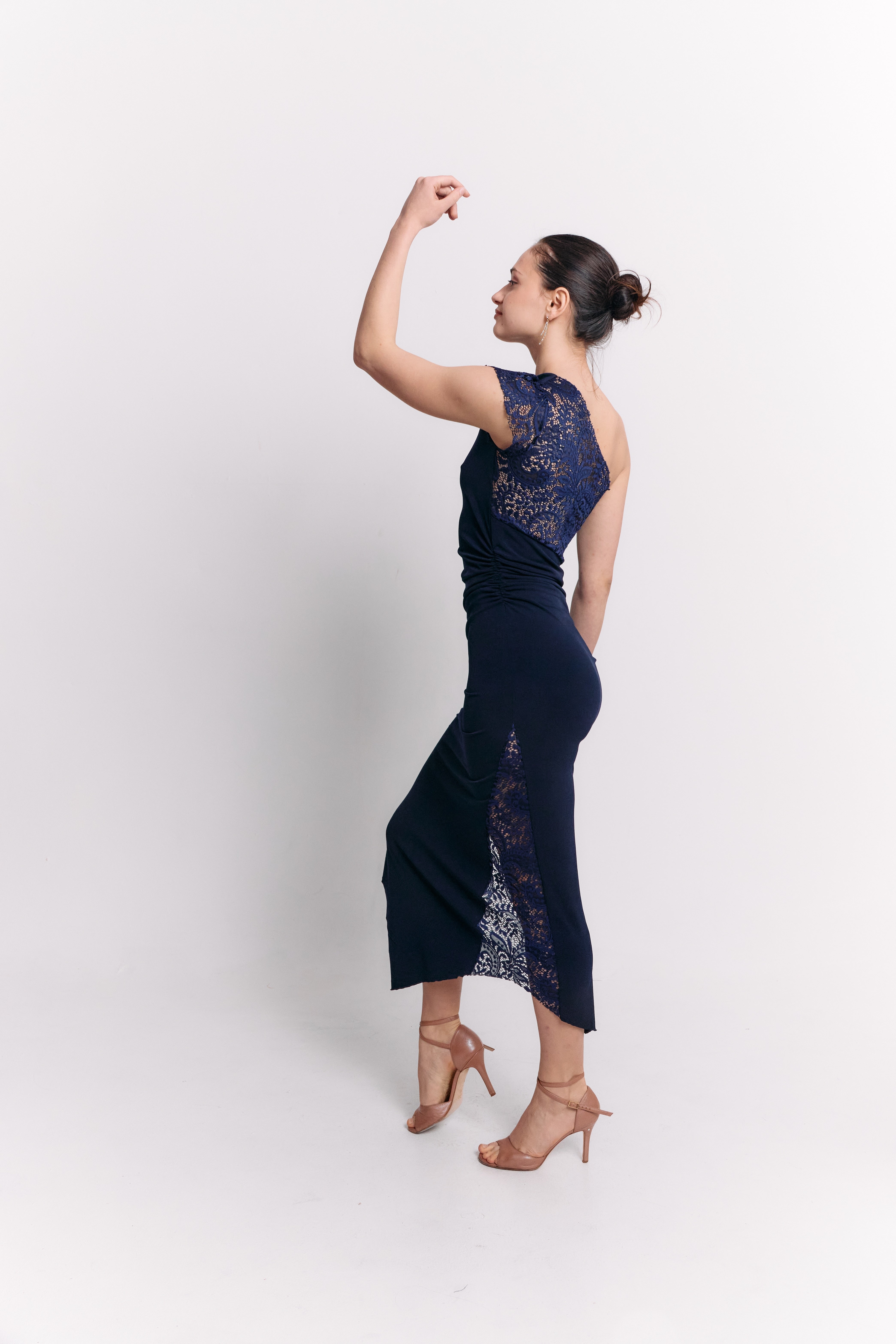 Woman wearing a navy blue lace dress against a white background