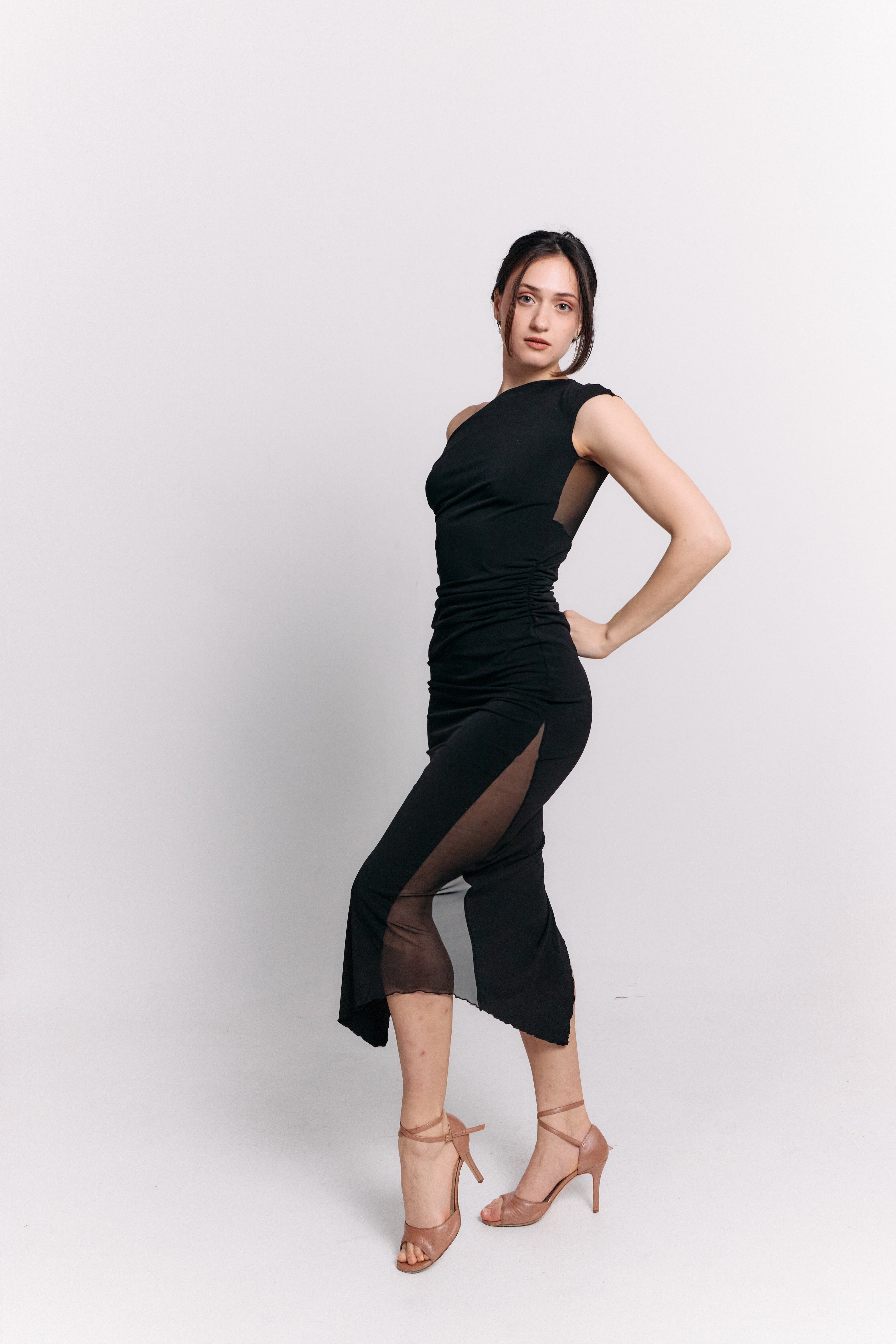 Woman wearing a black dress with sheer panels on a white background
