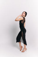 Woman wearing a black dress with sheer panels on a white background