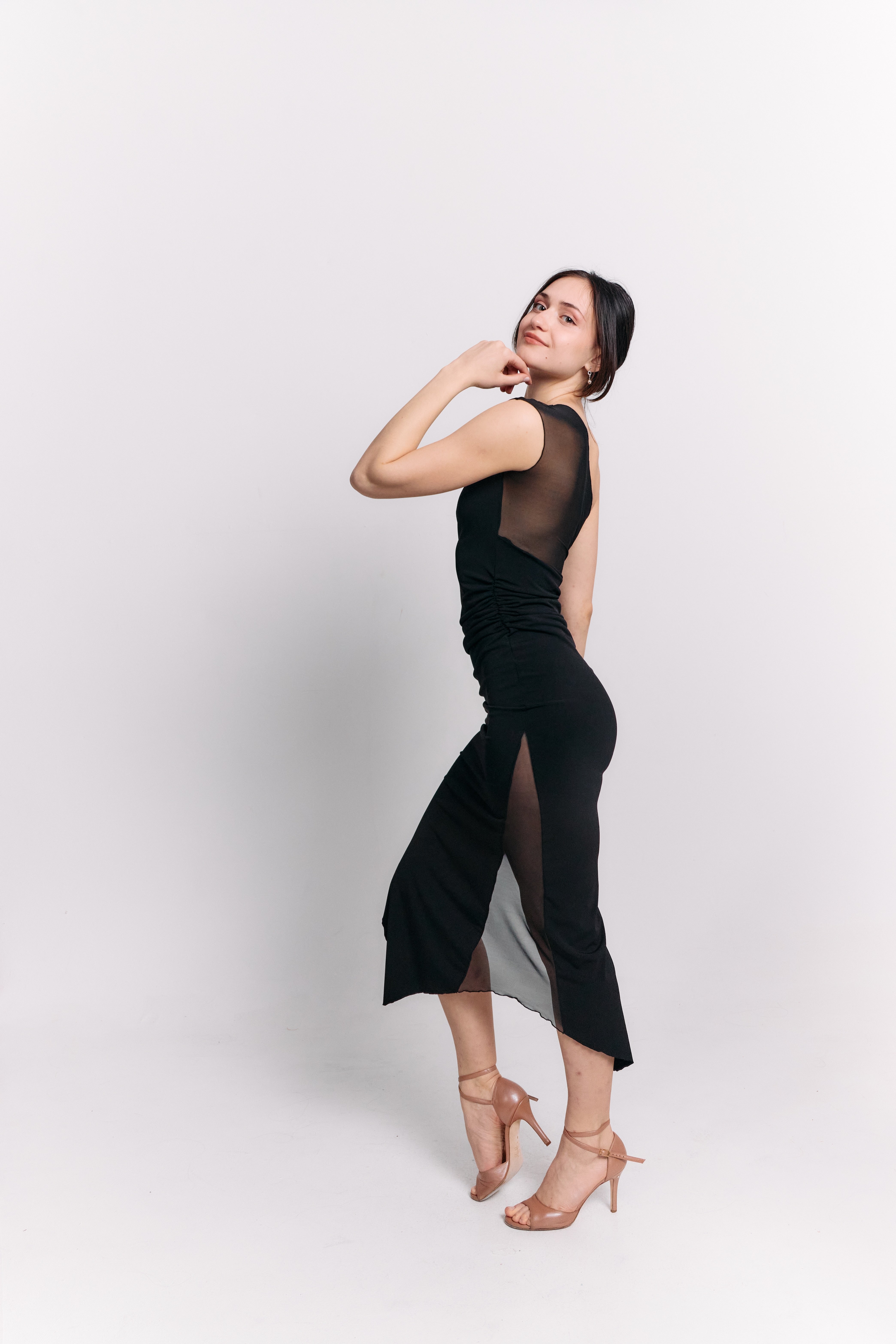 Woman wearing a black dress with sheer panels on a white background