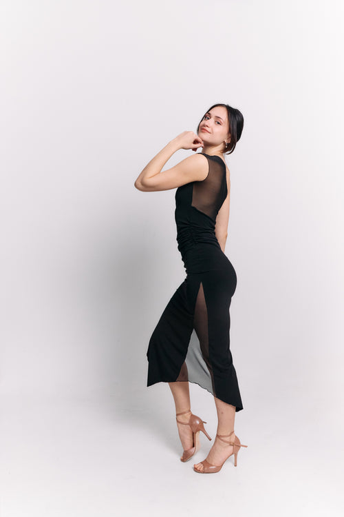 Woman wearing a black dress with sheer panels on a white background