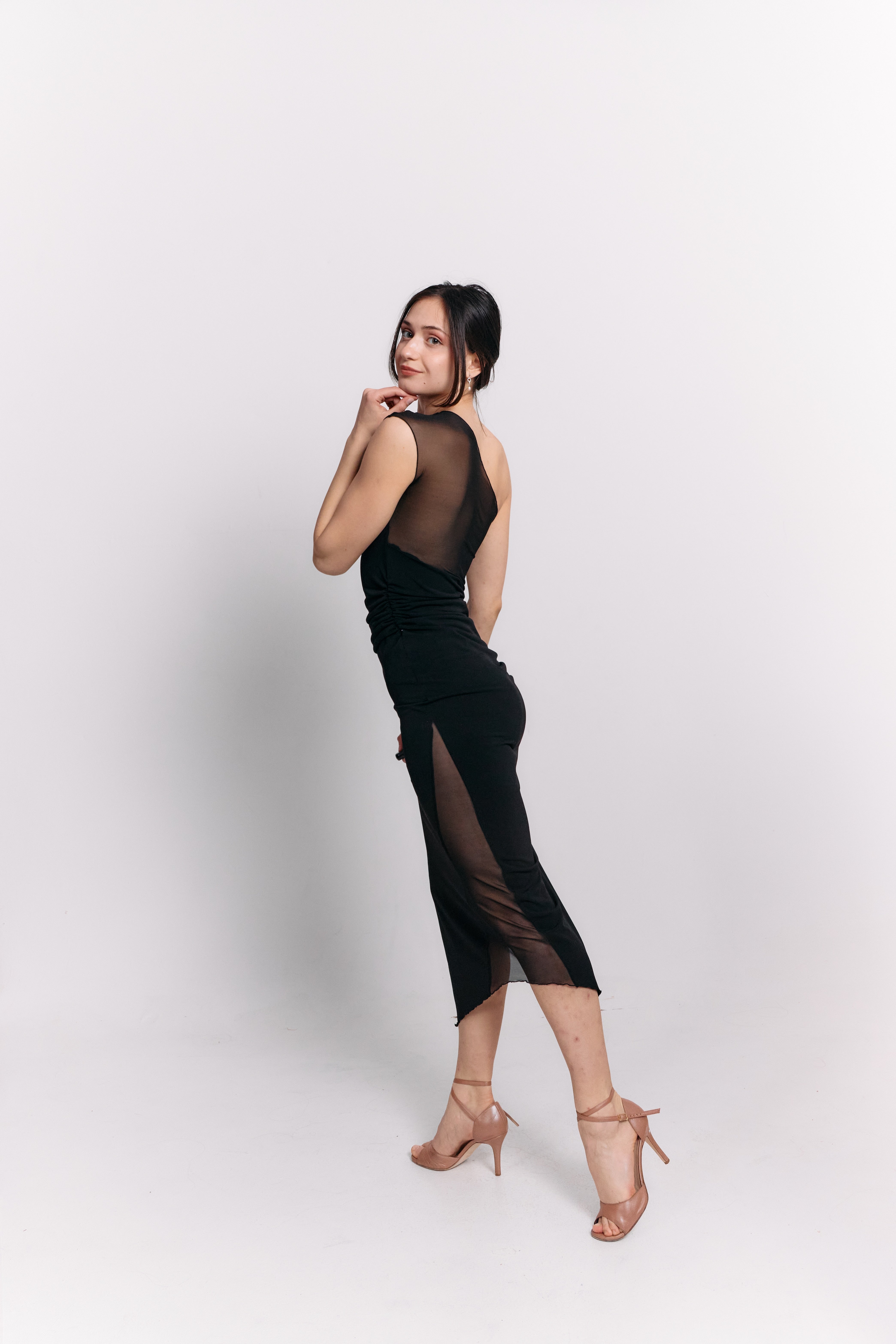 Woman wearing a black dress with sheer panels on a white background