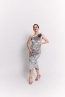 Woman wearing a silver one-shoulder dress against a white background
