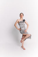 Woman wearing a silver one-shoulder dress with a floral detail on a white background