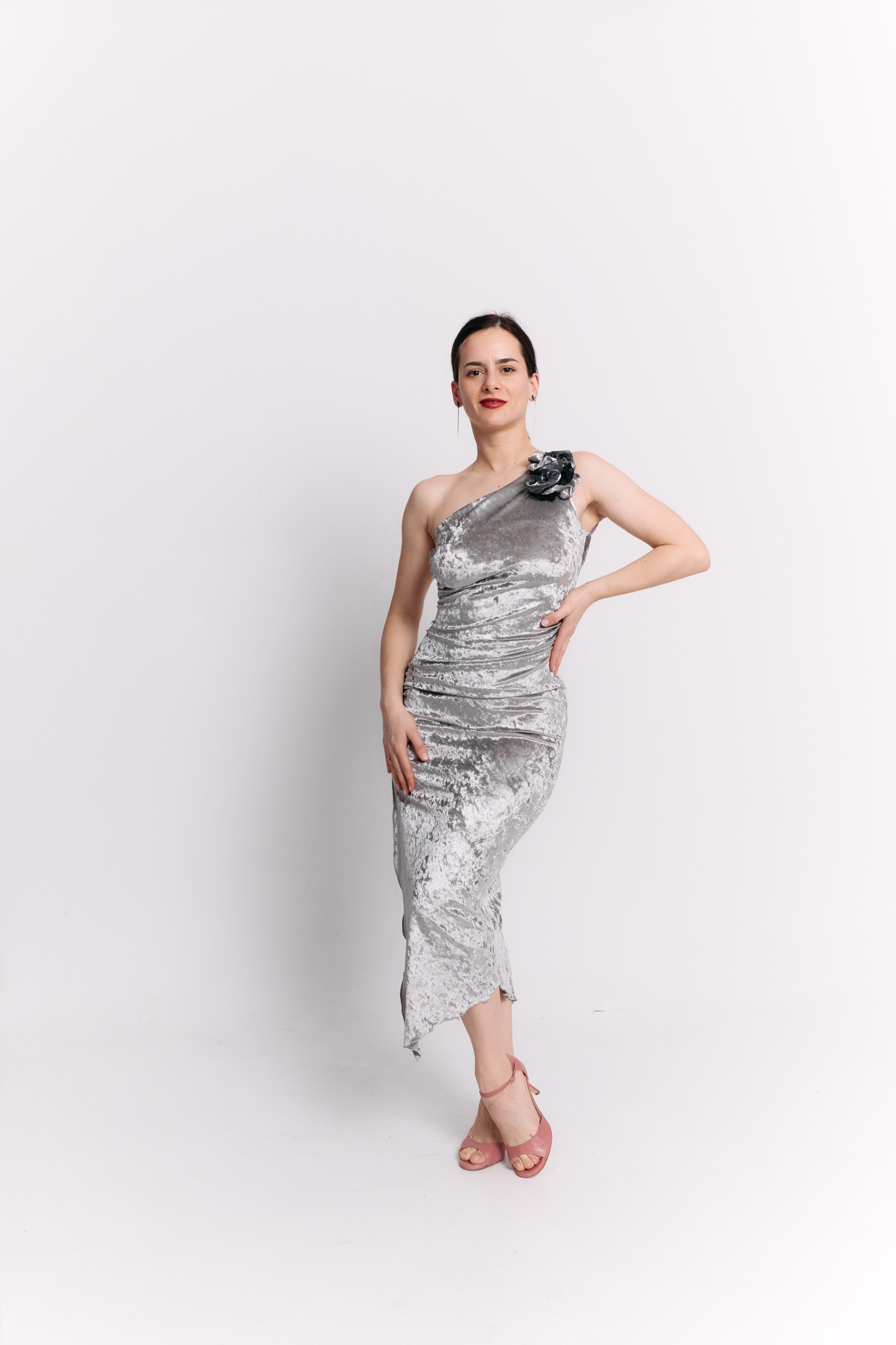 Woman wearing a silver one-shoulder dress on a white background