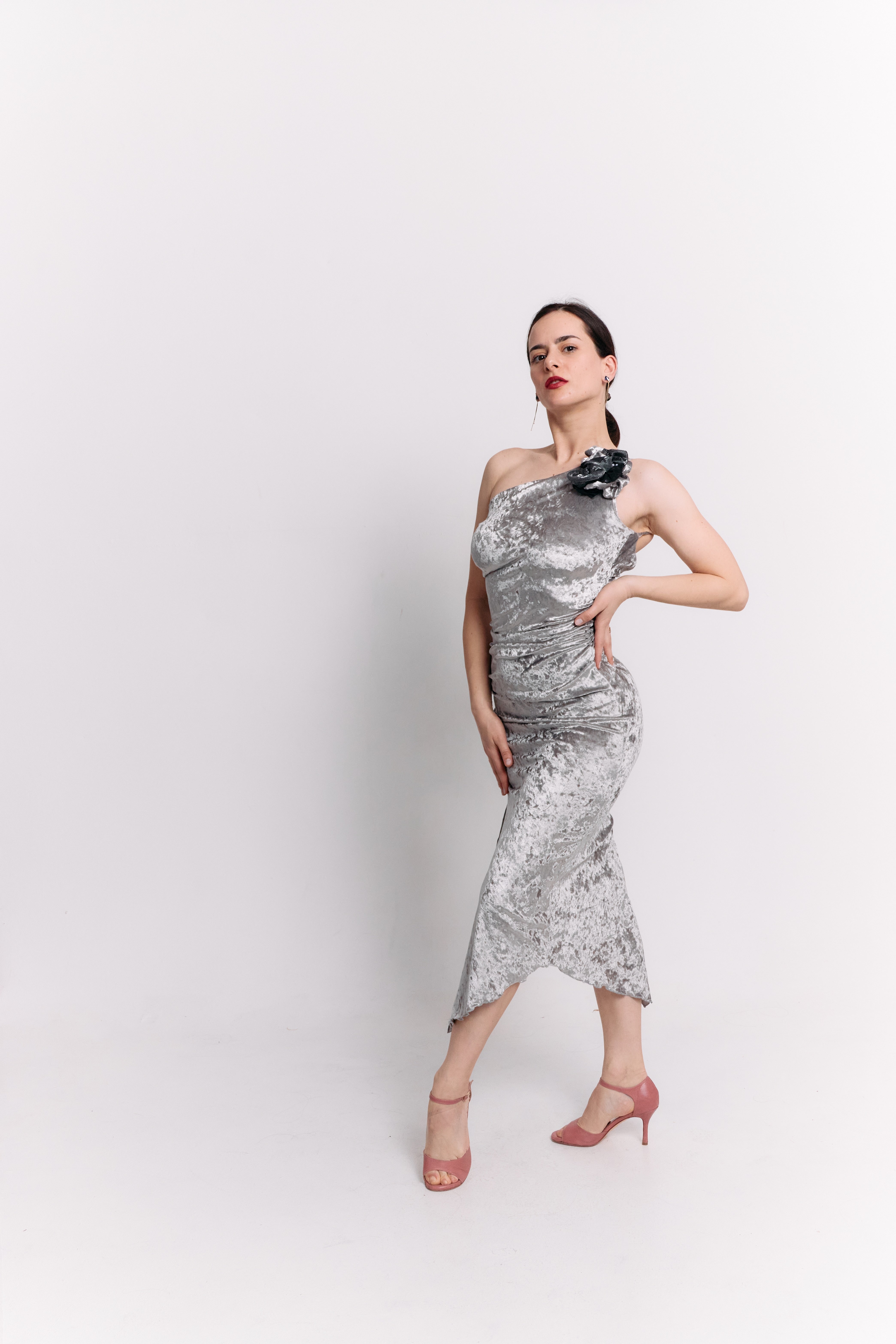 Woman wearing a silver dress with a flower detail on a white background